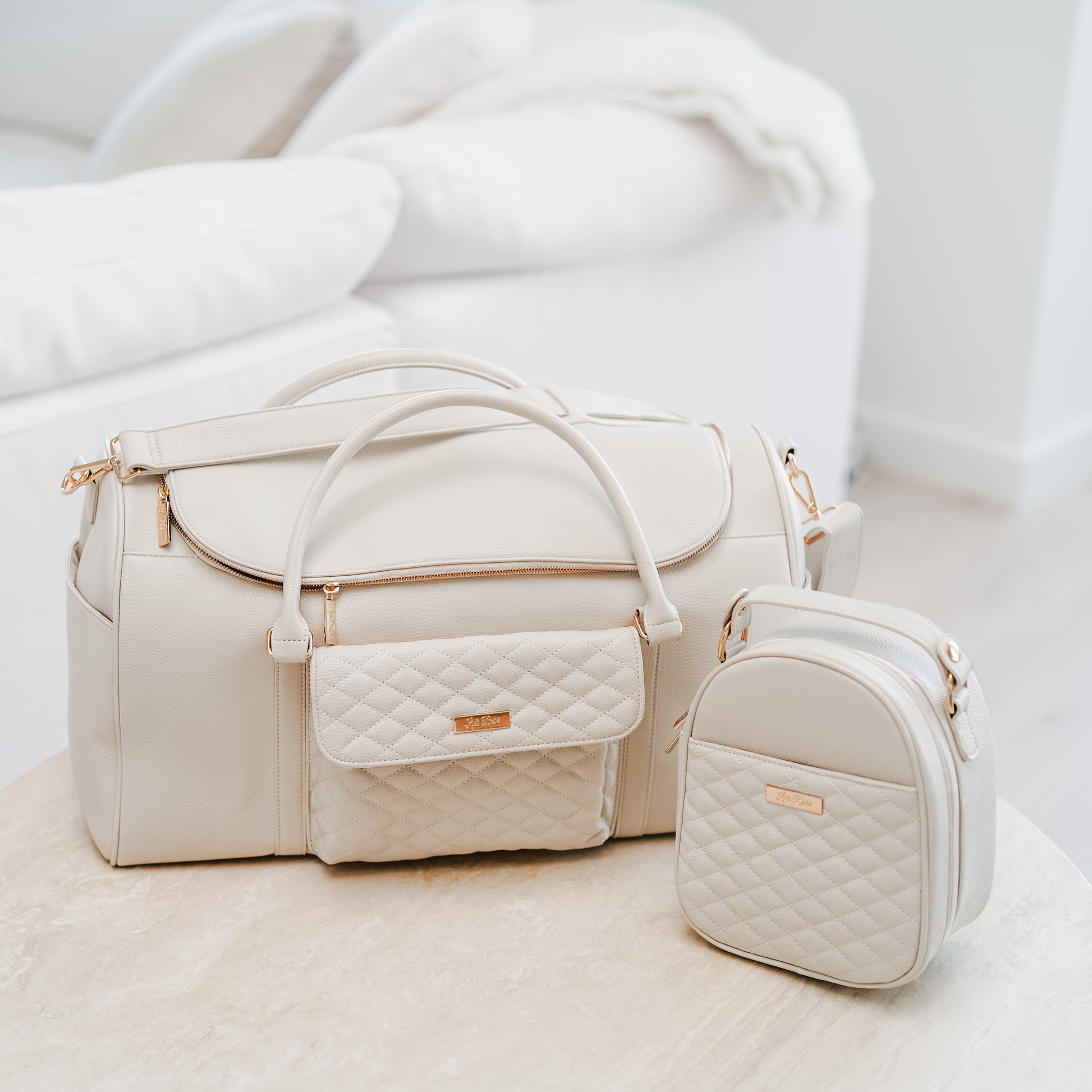 Set of cream-colored handbags with gold accents on a light background