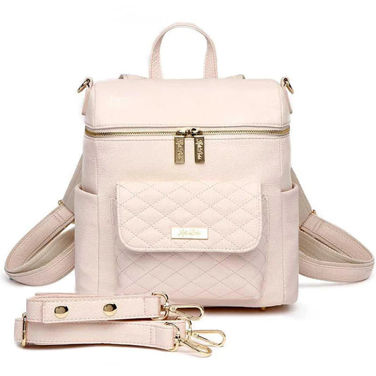 A pastel pink Petit Monaco diaper bag with a compact design, featuring premium vegan leather, a quilted pattern, and elegant gold-tone hardware.