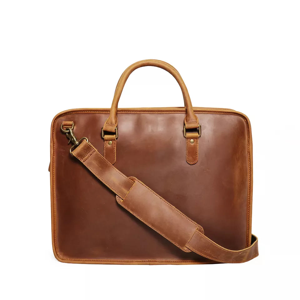 Brown leather briefcase with shoulder strap on a white background