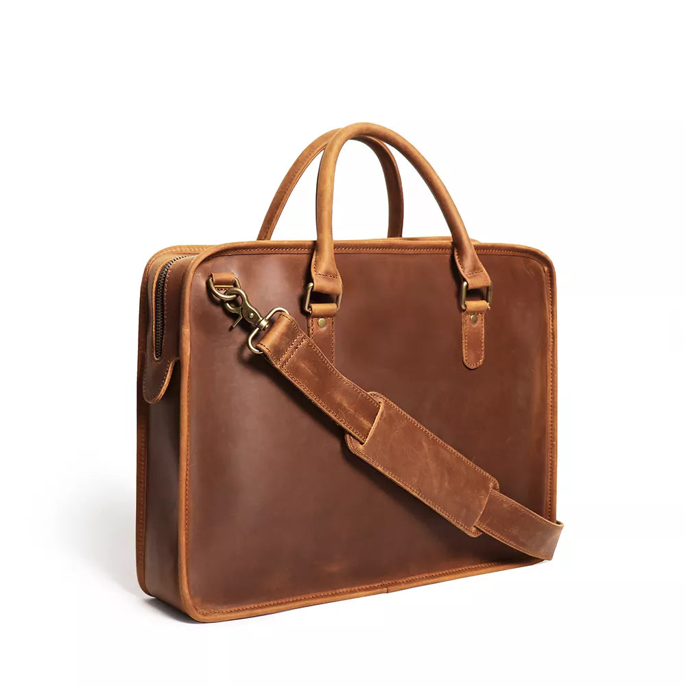 Brown leather briefcase with shoulder strap on a white background