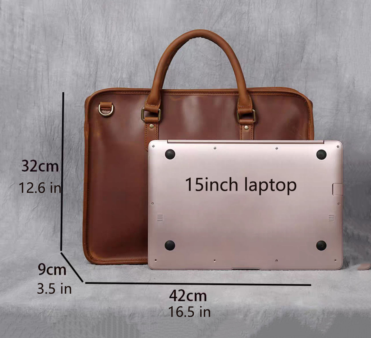 Brown leather briefcase next to a 15-inch laptop with dimensions indicated on a gray background