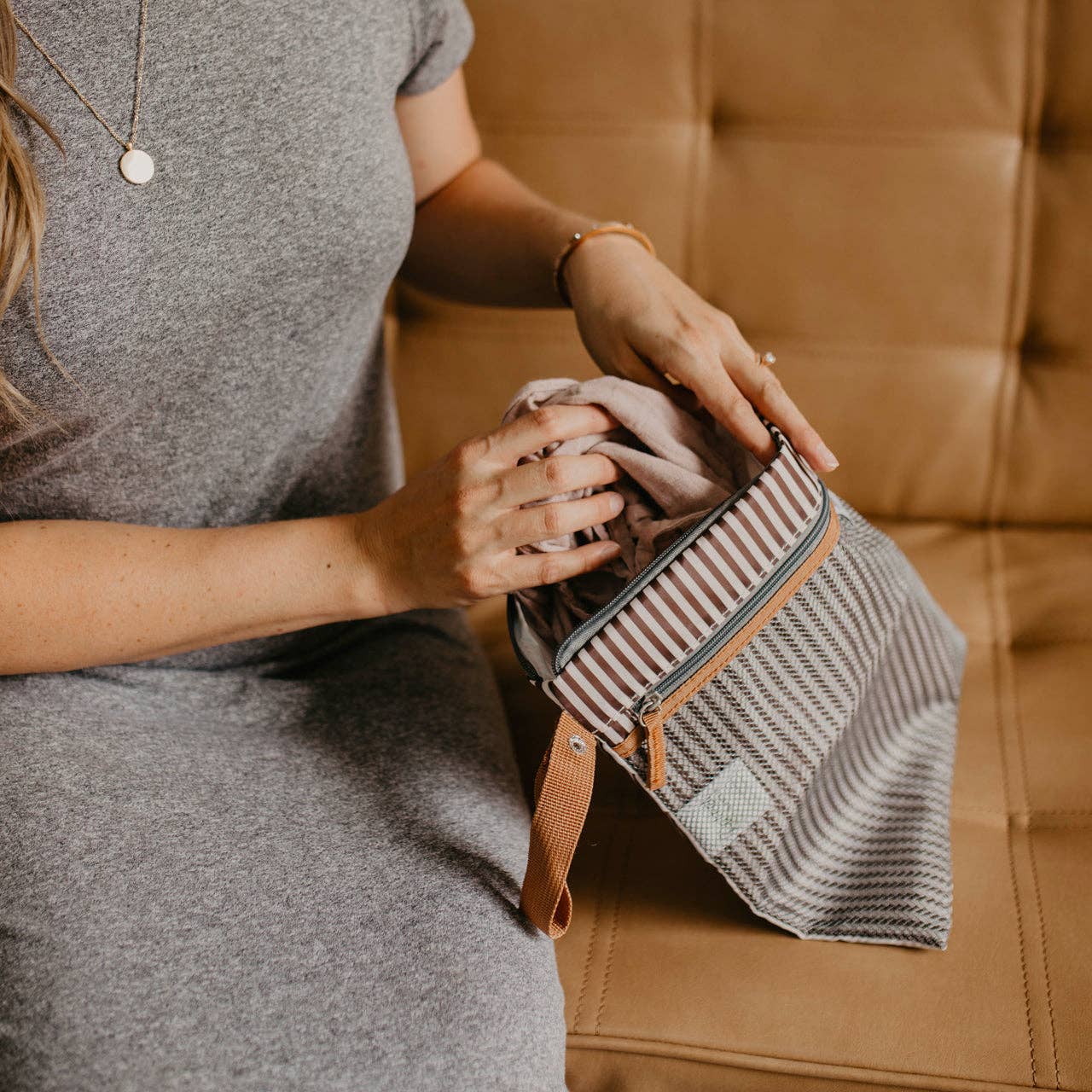 Person holding a striped bag on a brown couch