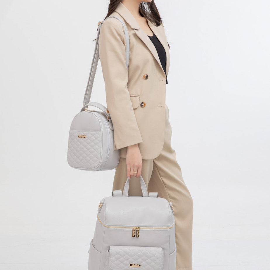 Person holding two gray bags with a plain background