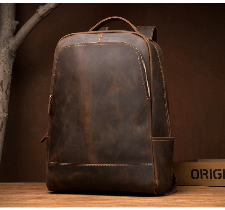 Brown leather backpack on a wooden surface with a dark brown background