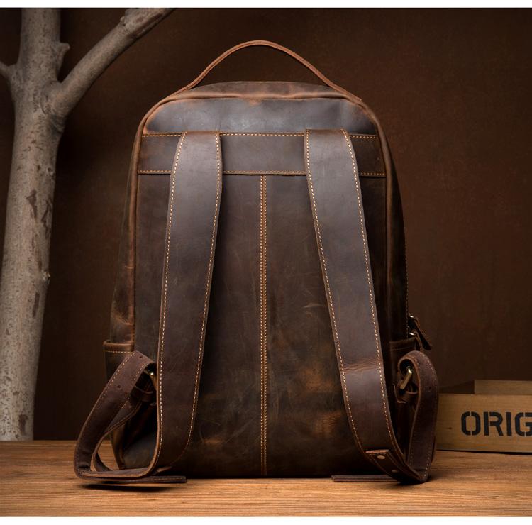 Brown leather backpack on a wooden surface with a dark brown background