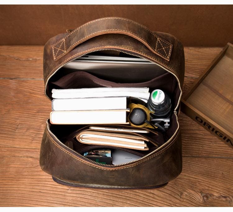 Brown leather bag with items inside on a wooden surface