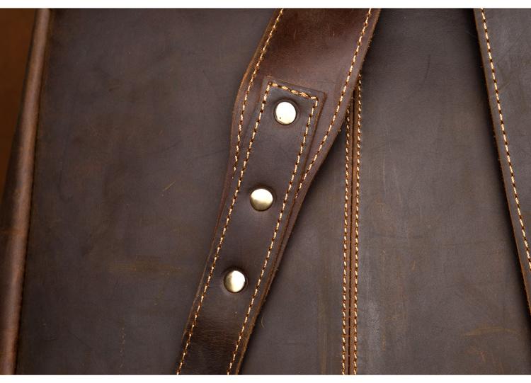 Close-up of a brown leather bag with gold stitching and silver buttons.